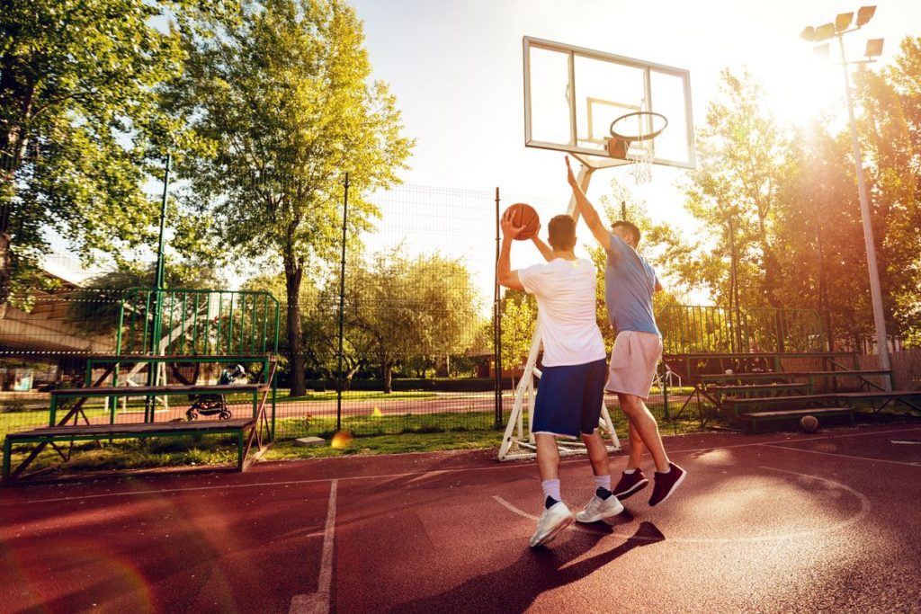 athletes playing basketball in a outdoor court